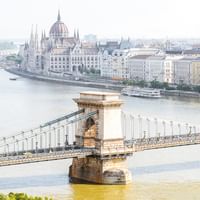 Chain Bridge and Parliament in Budapest Széchenyi Chain Bridge spanning the Danube River with Hungarian Parliament Building's distinctive dome visible in the background cityscape.