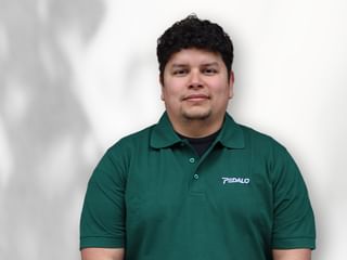 Porträt von Eric de Avila in einem grünen Poloshirt mit Pedalo-Logo, vor weißem Hintergrund stehend mit kurzen dunklen lockigen Haaren.