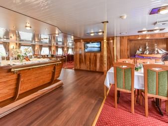 Eleganter Speisesaal an Bord der Florentina mit Holzbuffet, gedeckten Tischen mit grünen Stühlen und nautischen Dekorationen an holzgetäfelten Wänden.
