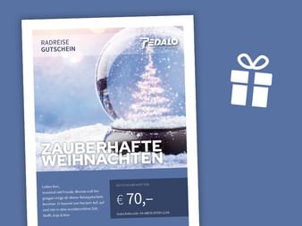 Weihnachtlicher Reisegutschein mit Schneekugel und beleuchtetem Weihnachtsbaum im Wert von €70. Blauer Hintergrund mit Geschenkbox-Symbol.