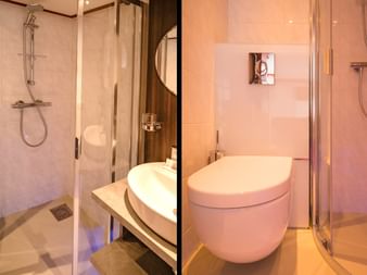 Kompaktes modernes Badezimmer auf Schiff Fluvius mit Glasduschkabine, wandhängendem WC, rundem Waschbecken auf Holztheke und beigen Fliesen.