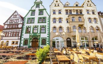 Bunte historische Gebäude in Thüringen mit Außengastronomie. Grünes Barockgebäude und cremefarbene Renaissancefassaden säumen den Platz.