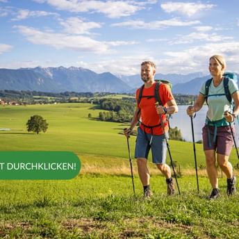 Wanderer wandern über Wiese mit See im Hintergrund
