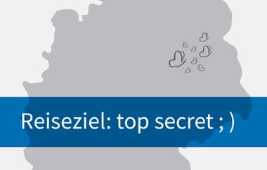 Graue Übersichtskarte mit blauem Banner mit deutschem Text 'Reiseziel: top secret ;)' und zwinkerndem Emoticon.
