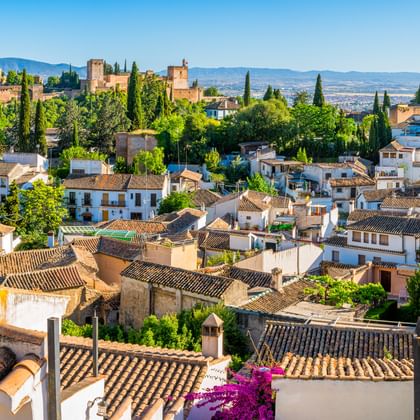Panoramablick auf Granada, Spanien mit traditionellen weißen Häusern mit Terrakotta-Dächern, Zypressen und der Alhambra-Palastanlage.