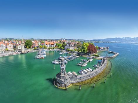 Luftaufnahme des Lindauer Hafens am Bodensee mit Steinmole, Löwenstatue, Leuchtturm, Yachthafen und historischer Altstadt.
