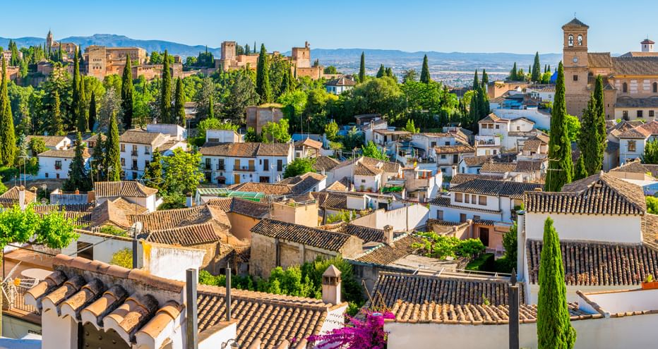 Panoramablick auf Granada, Spanien mit traditionellen weißen Häusern mit Terrakotta-Dächern, Zypressen und der Alhambra-Palastanlage.